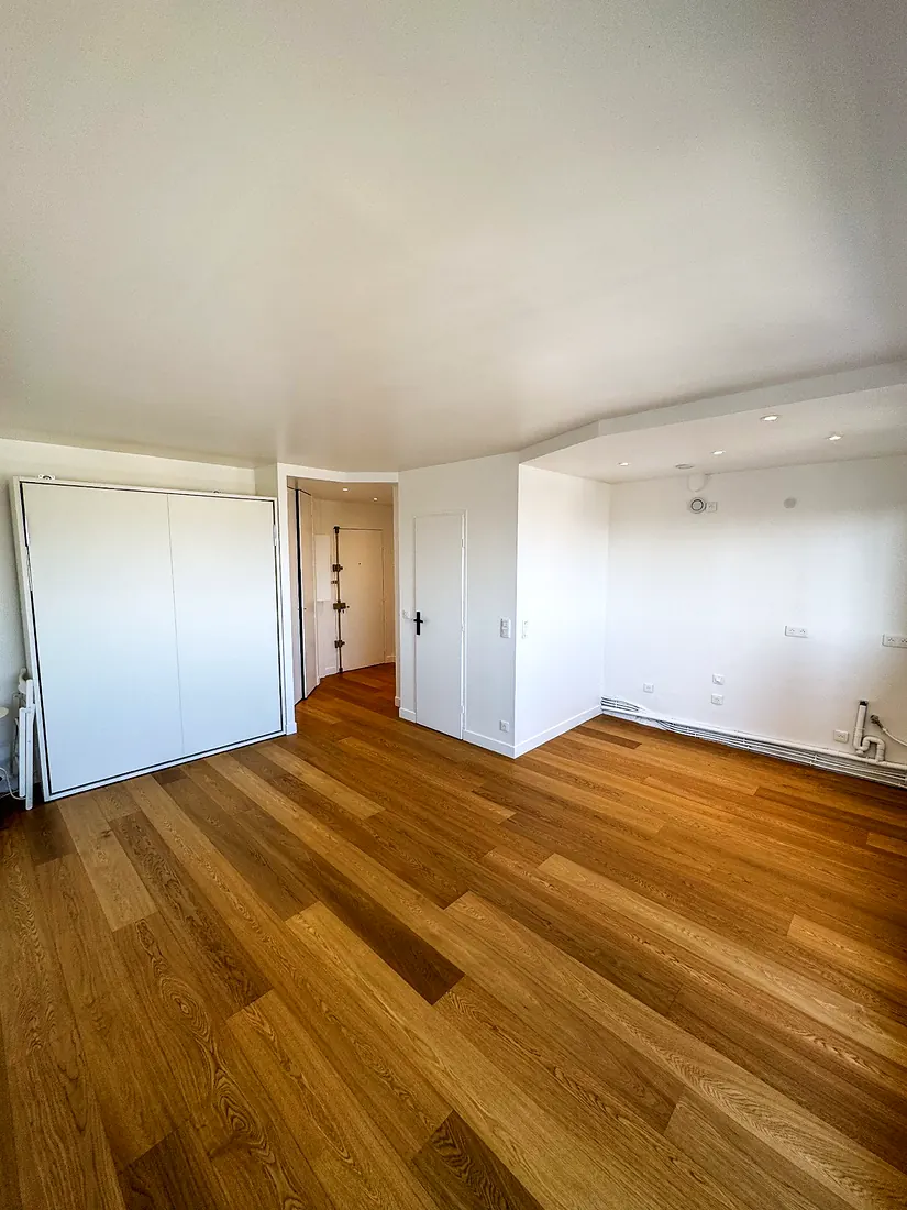 Le même studio, livré : parquet, cuisine ouverte et rangements intégrés.