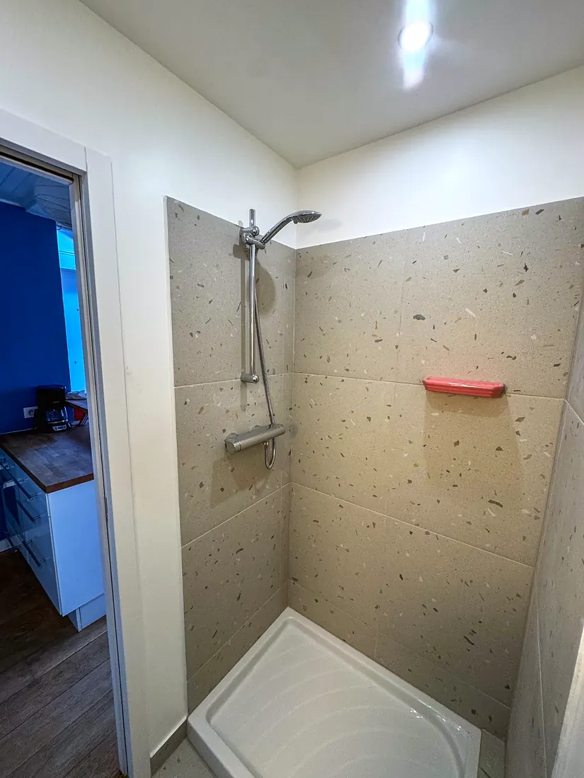 La même douche, livrée : faïence effet terrazzo et robinetterie thermostatique.